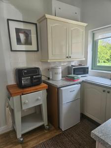 a small kitchen with white cabinets and a microwave at Yederick Barn in Sawdon