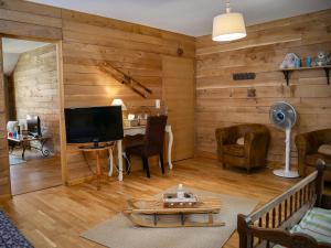 a living room with wooden walls and a television at Clos De La Gourmandière, Maison d'hôtes & Restaurant in Saint-Lothain