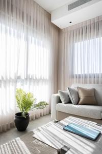 a living room with a couch and a plant at 2BR Balcony High Floor - Dizengoff Square View - MAMAD D80 in Tel Aviv