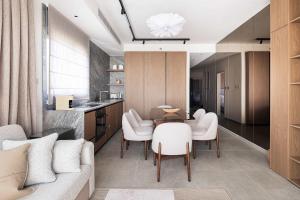 a living room with a table and white chairs at 2BR Balcony High Floor - Dizengoff Square View - MAMAD D80 in Tel Aviv