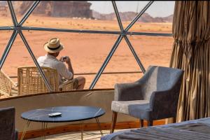 a man taking a picture of the desert from a window at WADI RUM NASA lUXURY BUBBLE in Wadi Rum