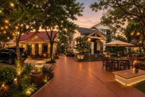 an outdoor patio with tables and chairs and trees at Pham's Homestay in Île de Trà Cổ