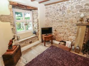 a living room with a stone wall and a television at The LA'AL Cragg in Kirkby Stephen