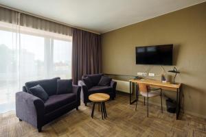 a hotel room with a couch and a desk and a tv at Liva Hotel in Liepāja