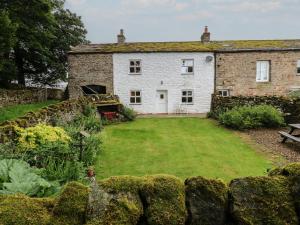 an old stone house with a garden in front of it at The LA'AL Cragg in Kirkby Stephen