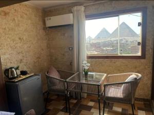 a room with a table and chairs and the pyramids at Vida Pyramids Inn in Cairo