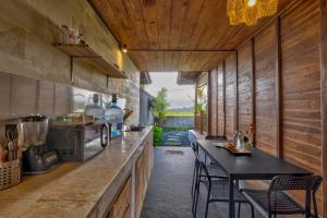 a kitchen with wooden walls and a counter with chairs at Uma Sunset Villa in Ubud