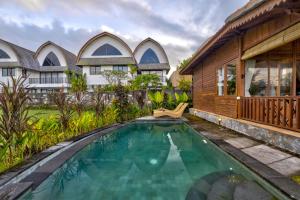 a swimming pool in front of a house at Uma Sunset Villa in Ubud