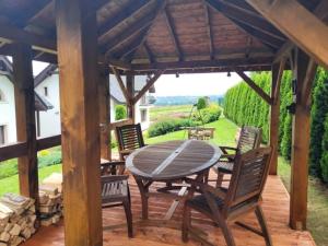 a wooden patio with a table and chairs on a deck at Domek na Cedrowej in Bierna