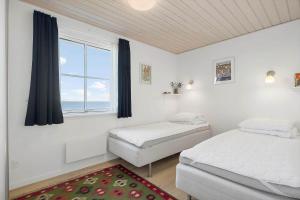two beds in a bedroom with a window and a rug at LF15113-Farso-Strandvejen-12-B in Farsø