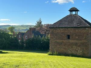 a brick building with a tower on a grass field at Rorrington Hall in Chirbury
