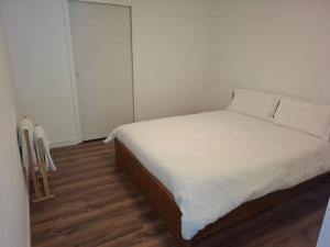 a bedroom with a bed with white sheets and wooden floors at Stable for two in Hégenheim