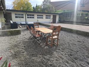 a wooden table with chairs and an umbrella in a yard at Stable for two in Hégenheim