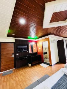 a large living room with a wooden ceiling and a television at Hotel La Gowri, Coorg in Madikeri