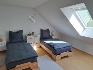 a attic bedroom with two beds and a window at Zum Nussbaum Wohnung Walnuss 86 qm 2 Schlafzimmer alles neu renoviert in Gerstetten