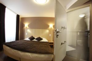 a bedroom with a bed and a door to a bathroom at Hotel De L'Abbaye in Sauxillanges