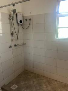 a bathroom with a shower with white tiled walls at Kilifi Hideaway,Spacious Coastal Retreat in Kilifi +13 photos