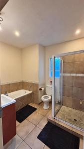 a bathroom with a tub and a toilet and a shower at Success Guesthouse in Nelspruit