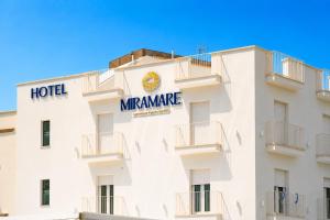 a white hotel with a sign on the side of it at Hotel Miramare in Porto Cesareo