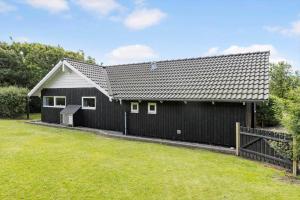 a black house with a fence and a yard at LF328-Vestervig-Gunhildsvej-28 in Vestervig