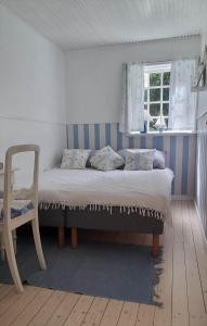 a bed in a room with a chair and a window at 10040-Rorvig-Lyngvaenget-10 in Rørvig
