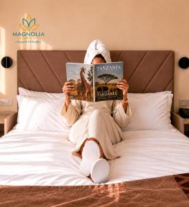 a person laying on a bed reading a book at Magnolia Suites B&B in Dar es Salaam