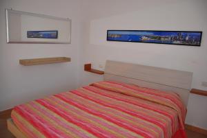 マリーナ・ディ・カンポにあるAppartamento La Baiaのベッドルーム1室(ベッド1台付)が備わります。壁に2枚の写真が飾られています。