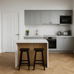 a kitchen with white cabinets and two bar stools at The Bridge York in York