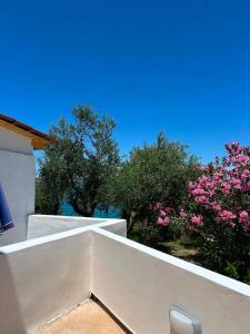 a white balcony with pink flowers and trees at Casa di Nonno in Alikanas