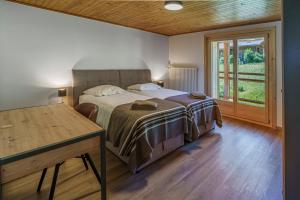 a bedroom with a bed and a table and a window at Chalet des Cheneaux in Bruson