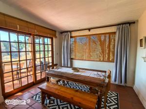 a dining room with a wooden table and windows at Critchley Common in Dullstroom
