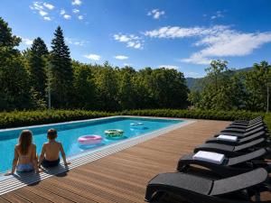 two girls sitting on a deck next to a swimming pool at Hotel Bardo in Bardo