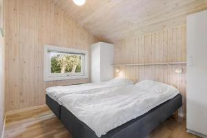 a bed in a room with wooden walls and a window at LF15147-Farso-Ramshule-47 in Farsø