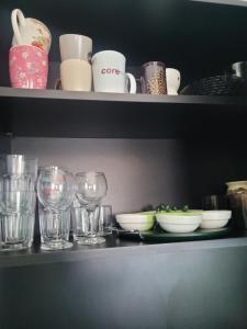 a shelf with glasses and plates and cups on it at Căsuța de vacanță in Eforie Sud