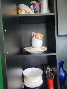 a shelf with a cup and plates in a kitchen at Căsuța de vacanță in Eforie Sud +12 photos