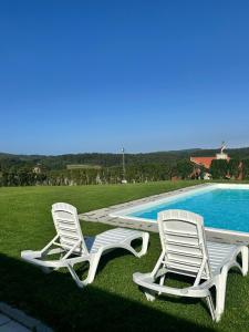 two white chairs sitting next to a swimming pool at Villa Cariño - Apartamento en Malpica de Bergantiños in Malpica
