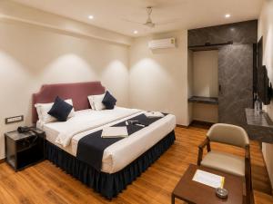 a bedroom with a bed and a table and a chair at Hotel Nee Residency in Rajkot