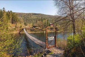 a suspension bridge over a river in a forest at Tinyhouse surrounding Norwegian mountains in Bergen