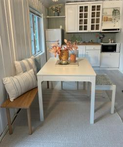 a white kitchen with a table and a bench at Tinyhouse surrounding Norwegian mountains in Bergen