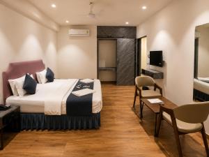 a hotel room with a bed and a table and chairs at Hotel Nee Residency in Rajkot