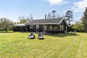a black house with two chairs in a yard at LF15194-Hojslev-Spaettevej-14 in Højslev