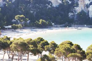 a beach with a bunch of people in the water at Comitas Floramar in Cala Galdana