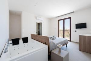 a white room with a bed and a bath tub at Aura - Stagnone Apartments in Marsala