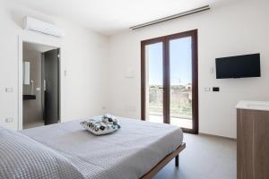 a white bedroom with a bed and a flat screen tv at Aura - Stagnone Apartments in Marsala