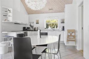 a white kitchen with a white table and chairs at 13328-Vig-Lillemosevej-5 in Vig