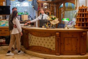 a man and a woman shaking hands at a counter at Alexander Hotel Alpine Wellness Dolomites in Molveno +56 photos