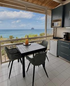 a kitchen with a table and chairs and the ocean at Studio Vigie 212 vue mer, accès piscine in Le Diamant +2 photos
