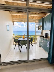 a kitchen with a table and a view of the ocean at Studio Vigie 212 vue mer, accès piscine in Le Diamant