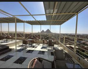 a balcony with chairs and tables and a view of the pyramid at Vida Pyramids Inn in Cairo