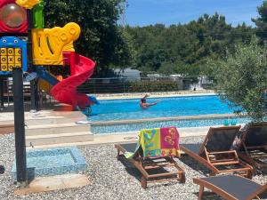a swimming pool with a playground with chairs and a slide at Camper Umma in Pula
